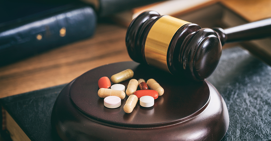 A judge 's gavel and pills on the table.